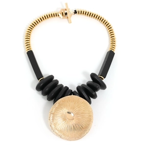Macro detail of a large golden sunburst pendant and beaded necklace with a toggle clasp