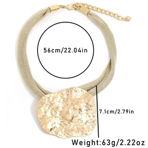 Detail view of bold gold mesh chain necklace with large hammered metal pendant and raw stone