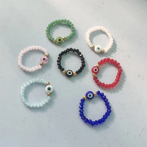 Set of seven bohemian elastic beaded evil eye rings in assorted vibrant colors