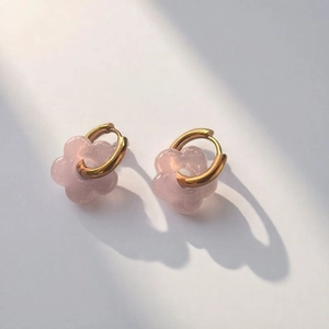 Pink glass flower earrings with gold hoops on a clean light gray background