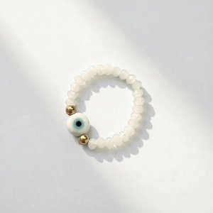 Ethnic style beaded elastic ring with translucent white crystals and blue evil eye charm