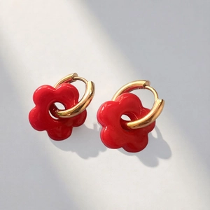 Detailed close-up of golden hoop earrings featuring vibrant red flower pendants