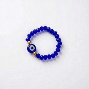 Detail of elastic beaded bracelet with blue evil eye charm and gold metal spacers