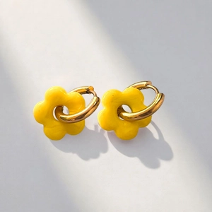 Detail of yellow flower drop earrings with golden rings on a modern grey background