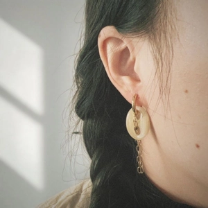 Boucles d'oreilles dorées avec pierre naturelle factice et glands à chaîne sur un modèle