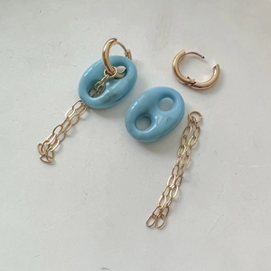 Vue macro des breloques en résine bleue et chaînes dorées démontées de la boucle d'oreille