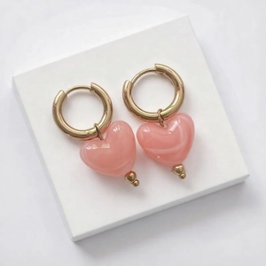 Détail des pendentifs cœur en résine rose translucide avec boucles d'oreilles dorées