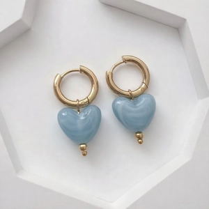 Détail des breloques cœur en résine avec motif marbré sur des boucles d'oreilles dorées