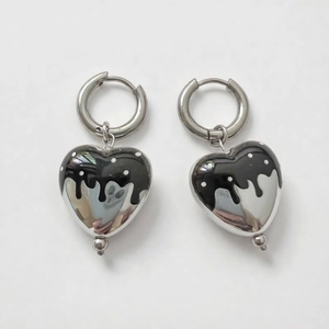 Dettaglio degli orecchini a cuore con smalto nero e pois bianchi su cerchi in argento