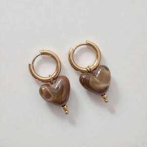 Gros plan détaillé de boucles d'oreilles dorées avec pendentifs cœurs en résine marbrée