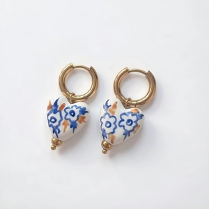 Macro detail of heart-shaped ceramic earring with hand-painted floral patterns and 18K gold hoop
