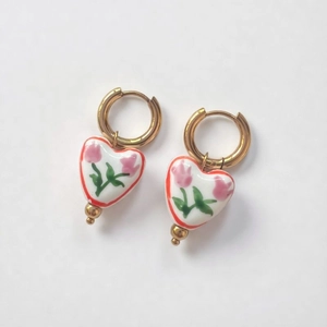 Macro shot of 18K gold-plated heart earrings with white ceramic tulip floral print