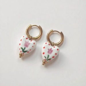 Close-up of ceramic heart earrings with pink tulip pattern and 18K gold-plated hoops