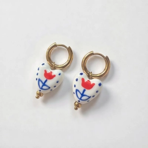 Detail of heart ceramic earrings with red tulip pattern and 18K gold-plated hoops