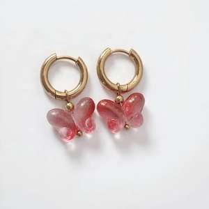 Detail of pink resin butterfly pendant on 18K gold stainless steel hoop earrings