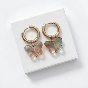 Macro view of butterfly earrings with 18K gold hoops and gradient resin charms