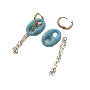 Boucles d'oreilles dorées avec maillons bleus et pompons à chaîne sur fond blanc immaculé