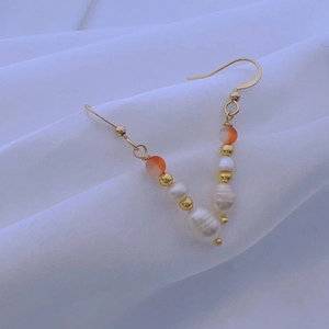 Detail of vintage gold earrings with orange beads and irregular baroque pearls
