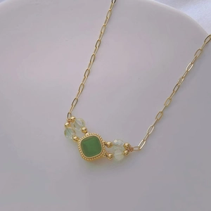 Elegant gold necklace with vintage green cat-eye pendant and delicate crystal beads
