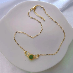 Detailed macro view of square green cat-eye pendant on gold paperclip link necklace