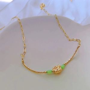 Detailed macro view of vintage gold necklace with green cat-eye beads and relief pendant