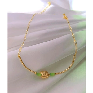 Detail of gold paperclip chain necklace with green cat-eye beads and textured gold sphere