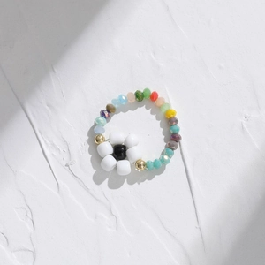 Detail of beaded flower ring featuring colorful seed beads and a white floral motif