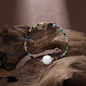 Bohemian colorful seed bead bracelet with white pearl charm on rustic wood display