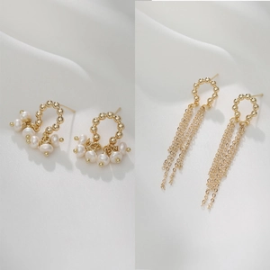 Detailed view of 14K gold baroque pearl C-ring and fringe tassel earrings on white silk