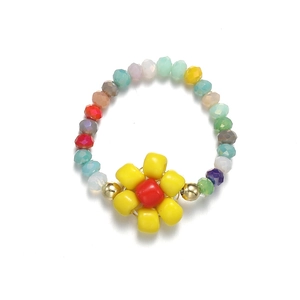 Macro view of a colorful seed bead elastic ring featuring a red and yellow sun flower