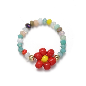 Detail of handmade beaded flower ring with colorful crystals and gold metal accents
