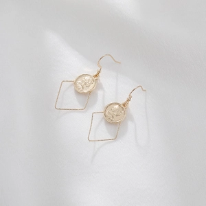 Vintage gold coin earrings with geometric charms and baroque pearl accents on fabric