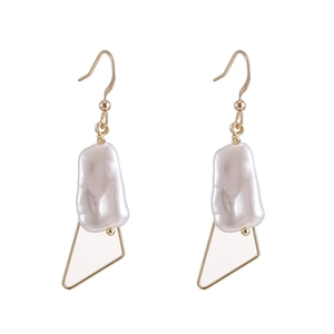 Detail of baroque pearl drop earrings with geometric gold frames and elegant texture