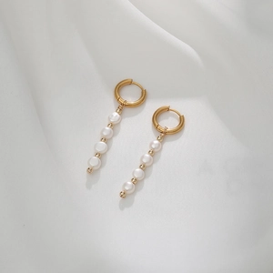 Détail de boucles d'oreilles géométriques en or avec cinq perles d'eau douce sur soie