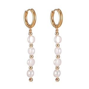 Détail de longues boucles d'oreilles dorées avec quatre perles blanches et accents