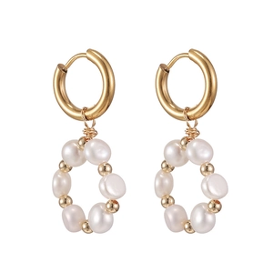 Vue macro de boucles d'oreilles dorées géométriques avec pendentifs circulaires en perles
