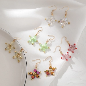 Five pairs of handmade beaded flower earrings with gold hooks on a white silk backdrop
