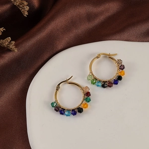 Close-up of handmade bohemian hoop earrings with colorful crystal beads on silk background