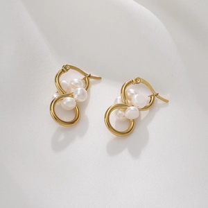 Close-up of gold stainless steel interlocking earrings with white pearls on silk