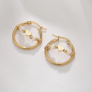 Detail of 18K gold hoop earrings with white pearls and a heart pendant on silk