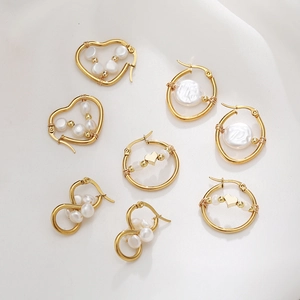 Macro detail of gold-plated brass heart and pearl earrings on white silk