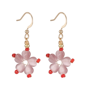 Close-up of pink cat eye stone flower earrings with gold hooks and red bead accents