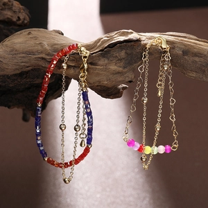 Double-layered colorful beaded bracelets with gold accents on a natural wood branch