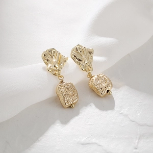 Detail of 14K gold hammered textured earrings on elegant white silk background