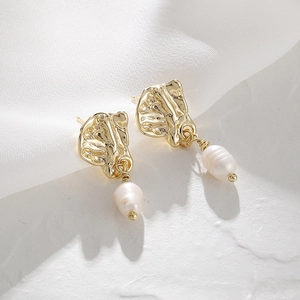 Macro view of 14K gold irregular lava texture studs and baroque pearl drop earrings