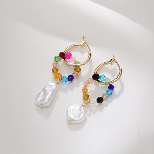 Detail of gold hoop earrings with colorful faceted crystal beads and baroque pearls