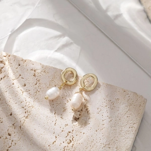 Detail of elegant baroque pearl drop earrings with golden hammered circle studs