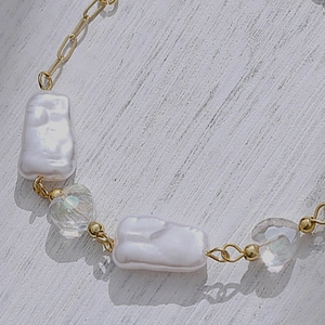 Elegant baroque pearl bracelet with crystal hearts and gold metal beads on wood
