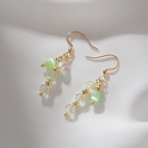 Vintage style cat eye stone gold drop earrings on white silk fabric background