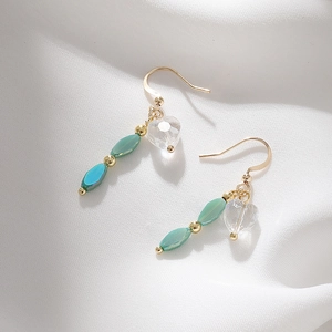Handmade heart and green turquoise drop earrings with gold hooks on white silk fabric